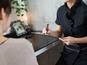 エステサロンでカルテに記入する女性エステティシャン